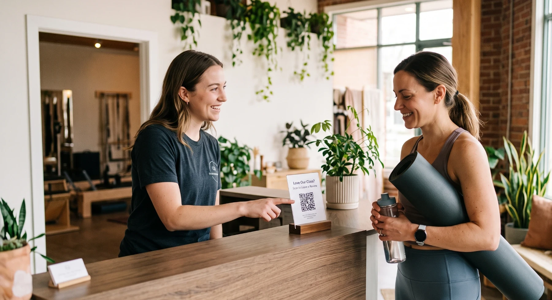 Front desk team member pointing a member to a QR code review stand after class